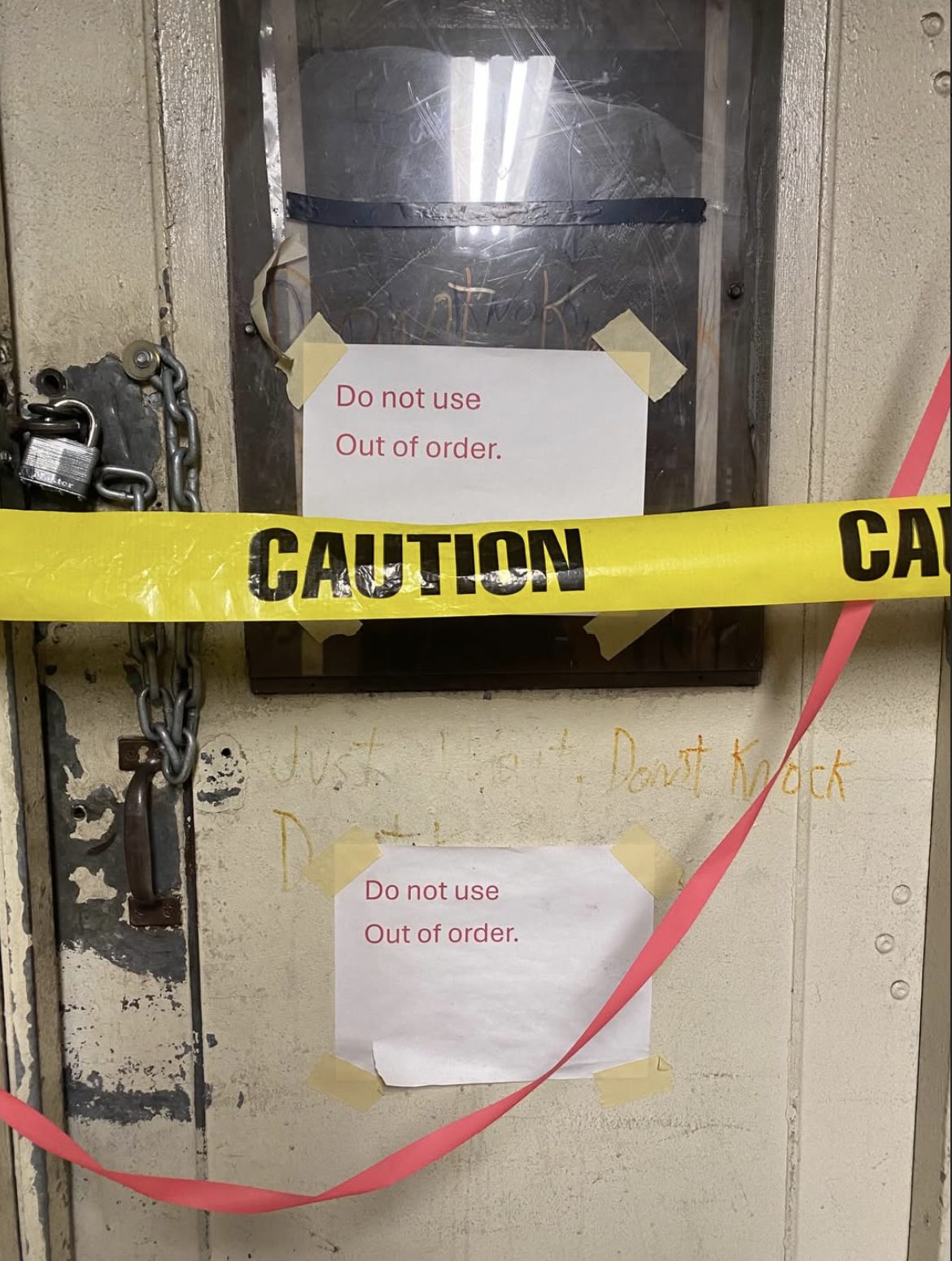 A chained door with two signs reading Do not use, out of order, crossed with caution tape